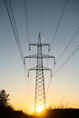 A line of high-voltage pillars through a plowed agricultural field Royalty Free Stock Photo