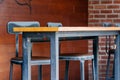 A line of industrial metal black chair stands beyond a long brown hard wood table at cafe or coffee shop interior Royalty Free Stock Photo