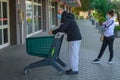 Line of italian people during coronavirus pandemic: social distancing of a couple queuing up with a shopping cart for groceries