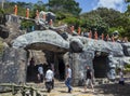 A line of monk statues and tourists head towards the The Golden Temple at Dambulla, Sri Lanka.