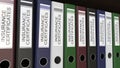 Line of multicolor office binders with Insurance certificates tags 3D rendering