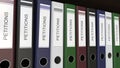 Line of multicolor office binders with Petitions tags 3D rendering Royalty Free Stock Photo