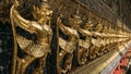 Line of ornate golden garuda statues on wall of The Emerald Buddha temple Wat Phra Kaew Grand Palace Bangkok Thailand. Royalty Free Stock Photo