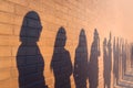 A line of shadows of people lined up against a red brick wall. Stand in a queue to the changes Royalty Free Stock Photo