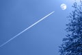 Line-shaped white cloud produced by flying aircraft aims at the day moon in the sky Royalty Free Stock Photo