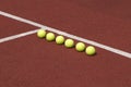 Line of six yellow tennis balls on court