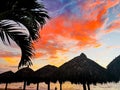 Tropical sunset with thatched huts and palm trees