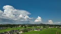 Line of towering cumulous clouds over quiet rural neighborhood and landscape