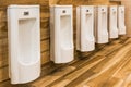 Line of white porcelain urinals in clean, Light public toilets