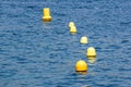 Line of yellow buoys against the blue sea. Restriction on open water. Glare and ripples on the water Royalty Free Stock Photo