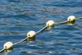 Line of yellow buoys against the blue sea. Restriction on open water. Glare and ripples on the water Royalty Free Stock Photo