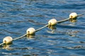 Line of yellow buoys against the blue sea. Restriction on open water. Glare and ripples on the water Royalty Free Stock Photo