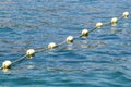 Line of yellow buoys against the blue sea. Restriction on open water. Glare and ripples on the water Royalty Free Stock Photo