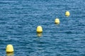 Line of yellow buoys against the blue sea. Restriction on open water. Glare and ripples on the water Royalty Free Stock Photo