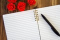 black pen on open lined blank note pad mock up with red rose pods