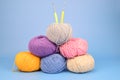 Lined with a pyramid, multi-colored skeins of wool. Two hooks are stuck into the top ball