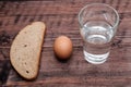 Lined with a row of bread, an egg and a glass of water, a very modest breakfast, money problems Royalty Free Stock Photo