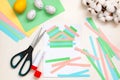 Lined strips of paper, multi-colored sheets, scissors, glue, Easter eggs on a light table. DIY concept. Step by step instructions Royalty Free Stock Photo