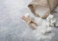 Linen bag of natural white refined sugar with cubes and wooden spoon on light table background Royalty Free Stock Photo