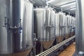 Lines of metal tanks in modern brewery. Shopfloor with brewery facilities. Manufacturable process of brewage. Mode of beer product