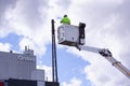 Lineworker working on power lines in crane bucket high in the air from aerial lift. A ÃËrsted power plant in the background. Sunny Royalty Free Stock Photo