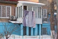 Lingerie dries in winter on a rope on the street, a blue house, bushes Royalty Free Stock Photo
