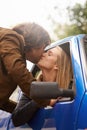 Lingering goodbyes. a young couple kissing each other goodbye through a car window.