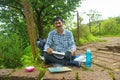 A middle-aged Indian man painting on a canvas in nature