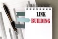 LINK BUILDING text on notebook with pen, calculator and chart on a grey background Royalty Free Stock Photo