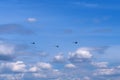 Link of three helicopters fly under white clouds in the blue sky