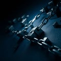 Linked chains with block treads form a circular pattern on a textured, dark blue Royalty Free Stock Photo