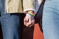 Linked hands of two women with a rainbow bracelet