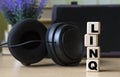 LINQ -word on cubes on the background of the tablet, headphones and a white cup