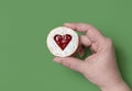 Linzer cookie in woman hand on a green background, above view Royalty Free Stock Photo