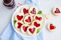 Linzer cookies with heart with raspberry jam and powdered sugar on a white plate with a cup of tea. Dessert on Valentine`s Day.