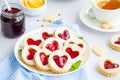 Linzer cookies with heart with raspberry jam and powdered sugar on a white plate with a cup of tea. Dessert on Valentine`s Day.