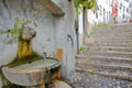 A lion`s head fountain in Alfama neighborhood with cobbled stairs in Lisbon, Portugal