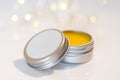 Lip balm in metal jar over light bokeh background