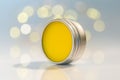 Lip balm in metal jar over light bokeh background