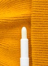Lip balm on the orange knitted background. Winter lip care stick with beeswax, honey, panthenol and shea butter. Copy space.