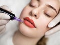 Lip Blushing. Cosmetologist applying permanent make up on lips of beautiful woman Royalty Free Stock Photo