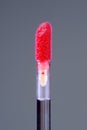 Lip Gloss Applicator with Scarlet Lip Gloss Close-Up on Grey Background