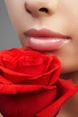 Lips with bright lipgloss makeup. Perfect clean skin, fresh lip make-up. Beautiful spa with tender pink rose flower Royalty Free Stock Photo