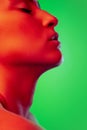 Beautiful east woman close up portrait isolated on green background in red neon light Royalty Free Stock Photo