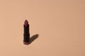 Lipstick on a beige background with shadow. Female cosmetic product for makeup