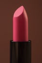 Lipstick of bright pink color in macro. Brown background
