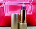 Lipstick with golden cover on red background