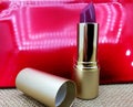 Lipstick with golden cover on red background