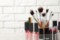 Lipstick holder with different makeup products on table against brick wall, closeup. Royalty Free Stock Photo