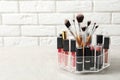 Lipstick holder with different makeup products on table against brick wall. Royalty Free Stock Photo